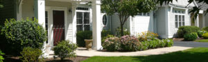 Exterior front view of a garden home with paved walkway and shrubs